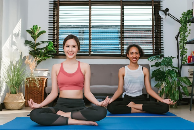 Mulheres adultas jovens fazendo exercícios de ioga em casa com amigos esporte e conceito de recreação