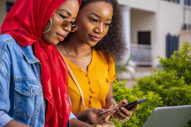 Mulheres africanas fazendo compras online enquanto estão sentadas em um parque