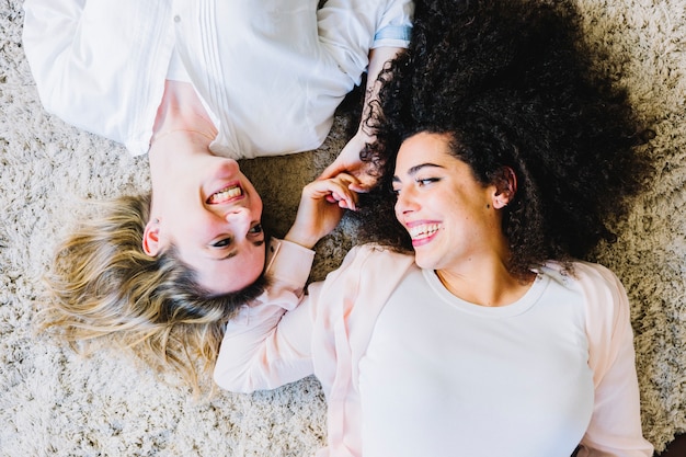 Foto grátis mulheres alegres no tapete olhando uns aos outros