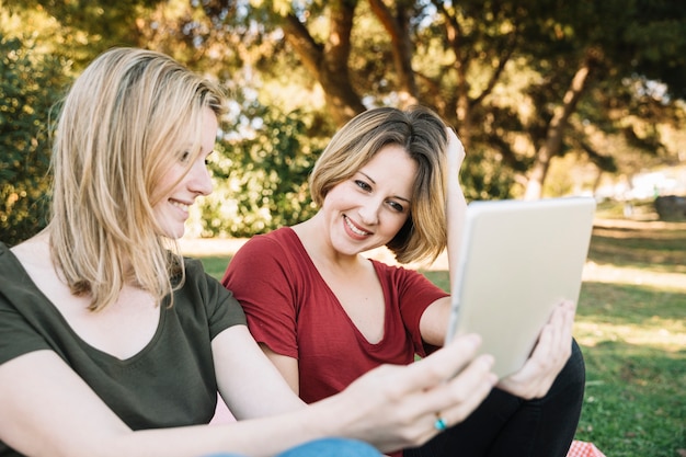 Foto grátis mulheres alegres, usando o tablet no parque