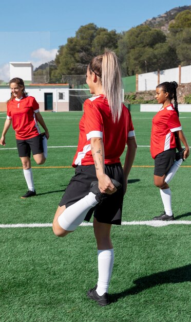 Mulheres alongando perna em campo de futebol