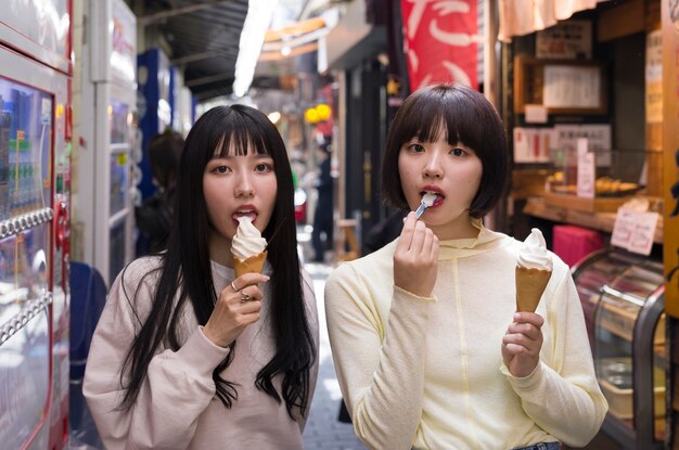 Mulheres asiáticas de tiro médio comendo sorvete