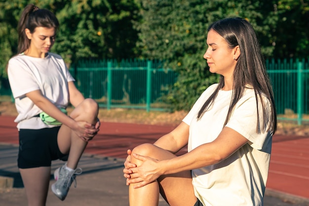 Mulheres atletas no estádio para esticar as pernas fitness e musculação aquecer