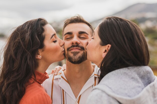 Mulheres beijando amigo masculino