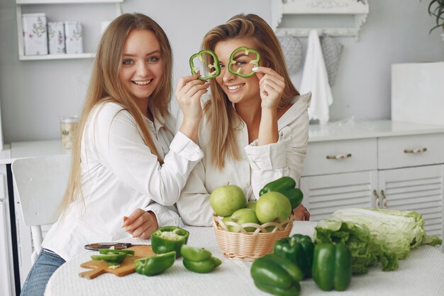 Mulheres bonitas e desportivas em uma cozinha com legumes