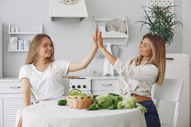 Mulheres bonitas e desportivas em uma cozinha com legumes