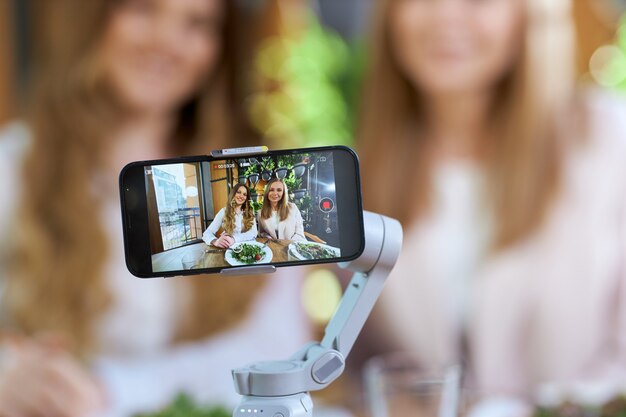 Mulheres bonitas e jovens blogueiras posando para a câmera do telefone