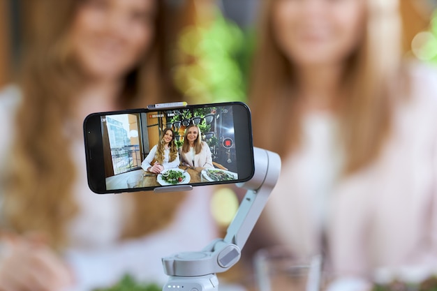 Mulheres bonitas e jovens blogueiras posando para a câmera do telefone