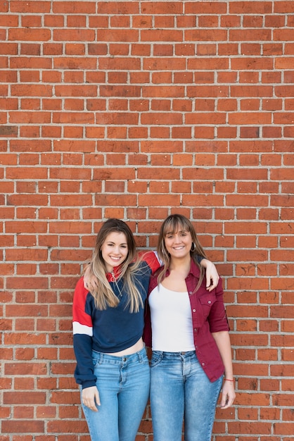 Mulheres bonitas posando com parede de tijolo