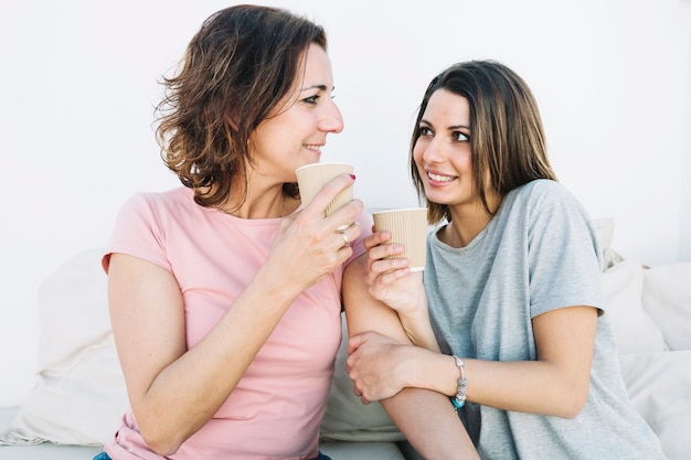 Mulheres, com, bebidas quentes, olhando um ao outro