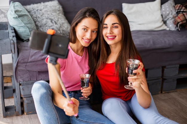 Mulheres com copo de vinho tomando selfie