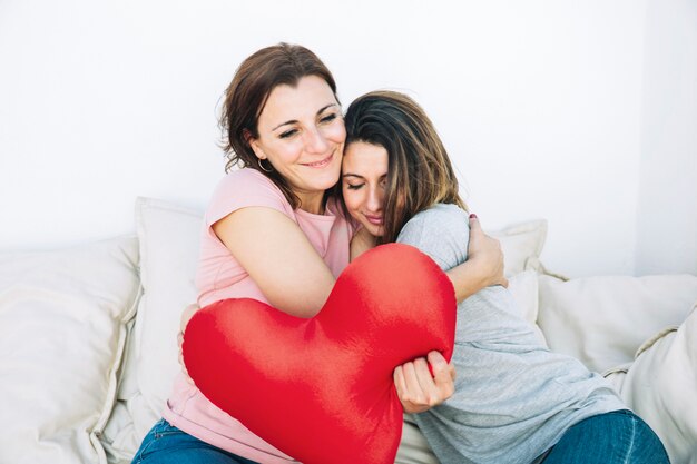 Mulheres com coração de pelúcia abraçando no sofá