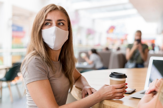 Mulheres com máscara trabalhando e bebendo café