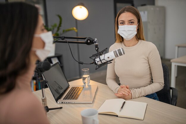 Mulheres com máscaras médicas em um estúdio de rádio