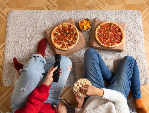 Mulheres com pipoca e pizza de perto