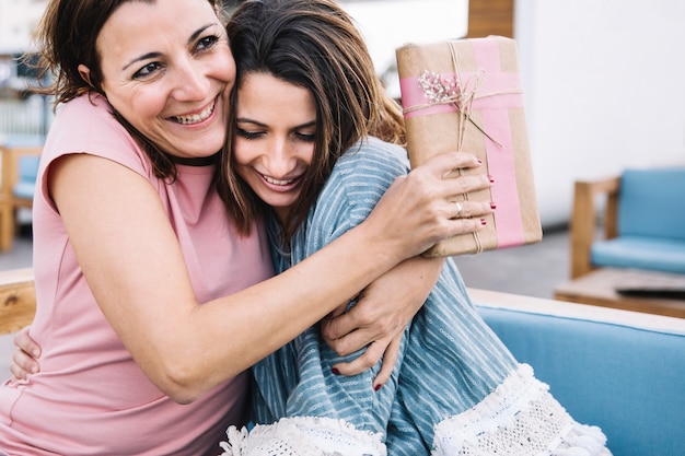 Foto grátis mulheres, com, presente, abraçando, ligado, sofá