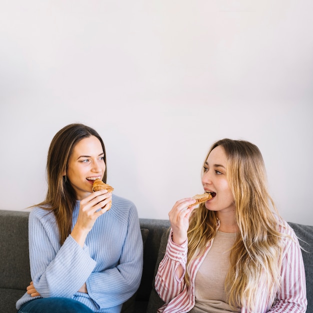 Mulheres comendo pastelaria no sofá