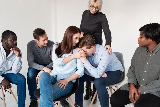 Mulheres consolando paciente de reabilitação masculina