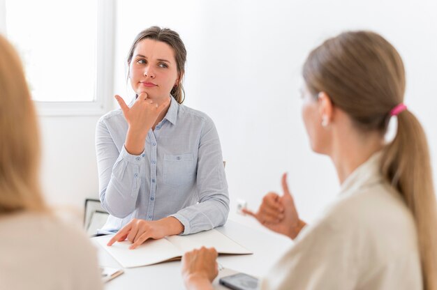 Mulheres conversando à mesa usando linguagem de sinais