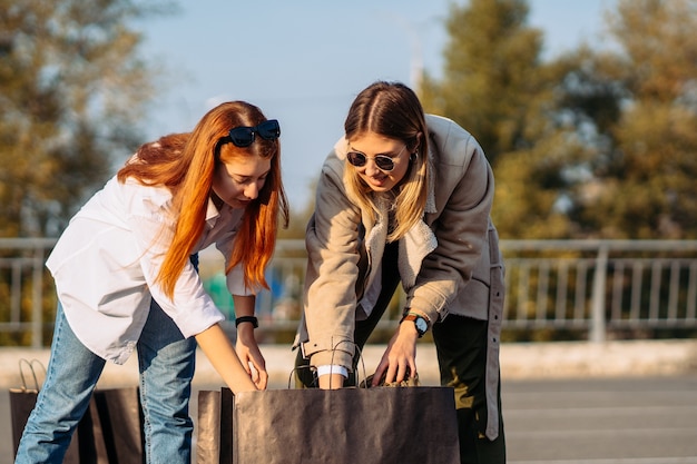 Mulheres da moda jovem com sacolas de compras no estacionamento