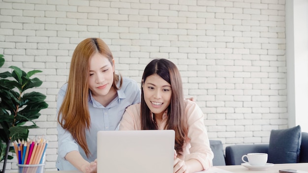 Foto grátis mulheres de negócios asiáticos criativos inteligentes atraentes em casual desgaste inteligente trabalhando no laptop enquanto está sentado