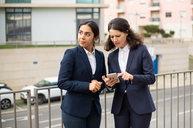 Mulheres de negócios concentradas usando smartphone