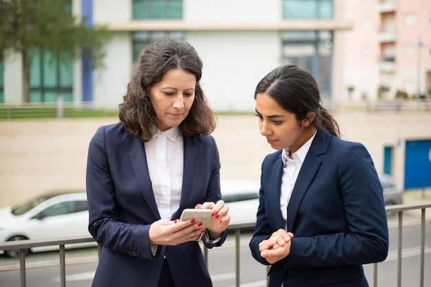 Mulheres de negócios focalizadas usando smartphone