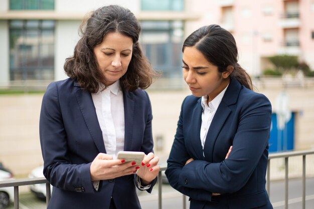 Mulheres de negócios sérias usando smartphone