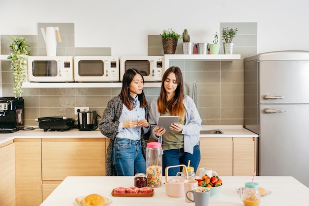 Mulheres de pé e assistindo mesa na cozinha