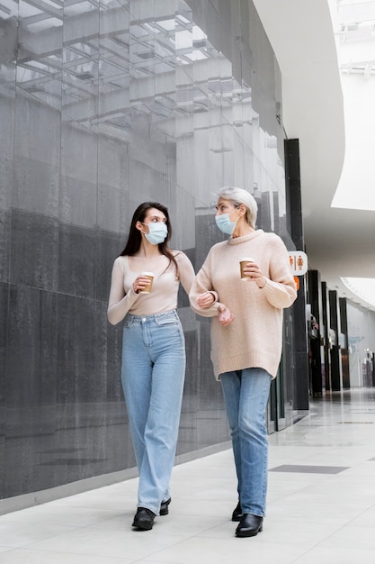 Mulheres de tiro completo com máscaras caminhando juntos