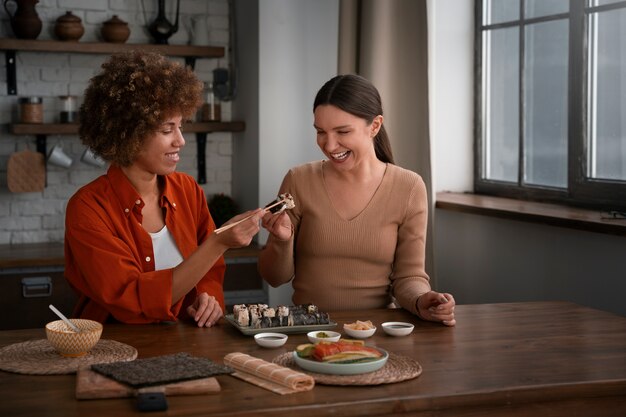 Mulheres de tiro médio aprendendo a fazer sushi