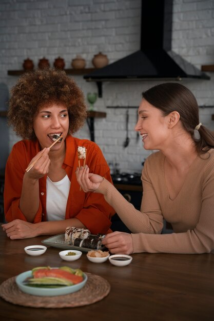 Mulheres de tiro médio aprendendo a fazer sushi