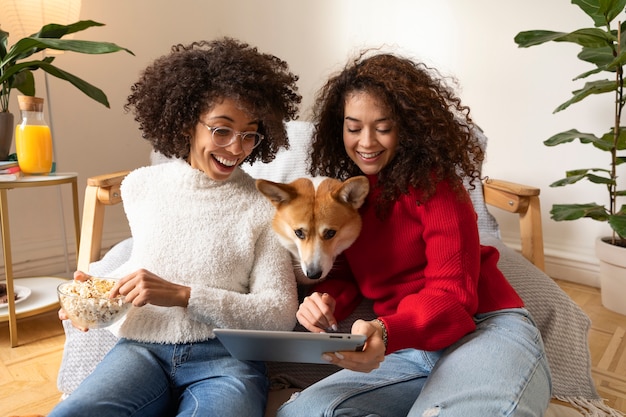 Mulheres de tiro médio e cachorro assistindo filmes