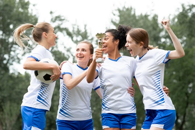 Mulheres de tiro médio segurando uma taça de ouro