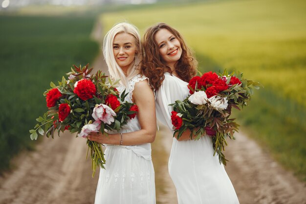 Mulheres de vestido elegante em pé em um campo de verão