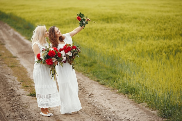 Mulheres de vestido elegante em pé em um campo de verão