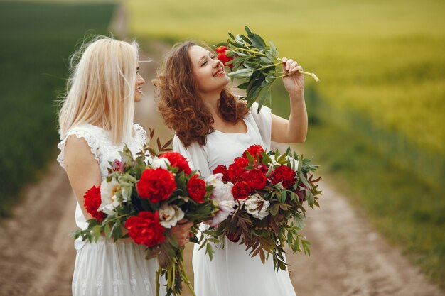 Mulheres de vestido elegante em pé em um campo de verão