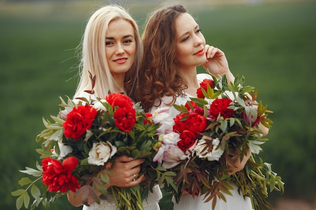 Mulheres de vestido elegante em pé em um campo de verão