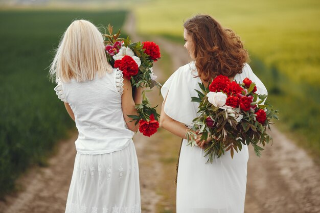 Mulheres de vestido elegante em pé em um campo de verão