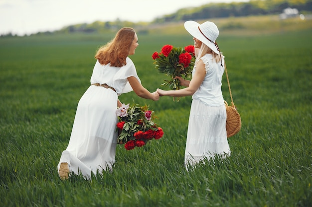 Mulheres de vestido elegante em pé em um campo de verão