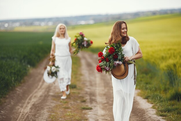 Mulheres de vestido elegante em pé em um campo de verão