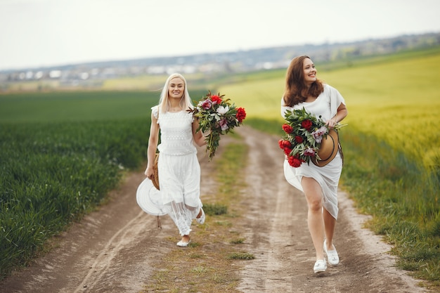 Mulheres de vestido elegante em pé em um campo de verão