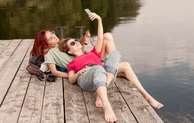 Mulheres deitadas na doca e tirando selfie