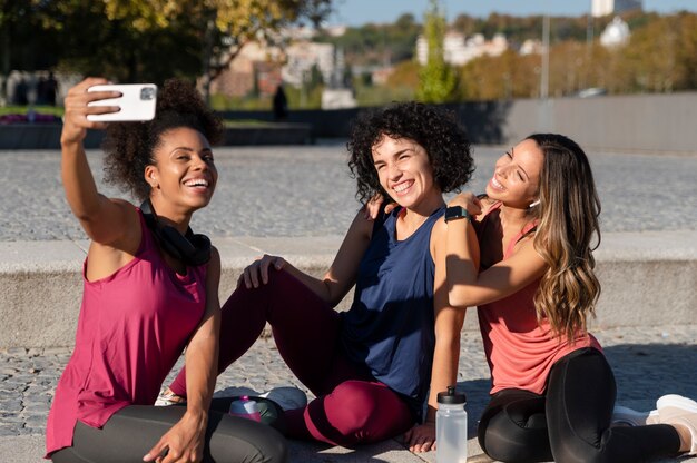 Mulheres desportivas com tiro médio tirando selfie