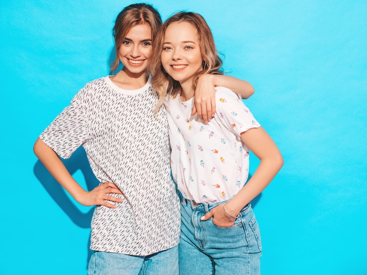 Foto grátis mulheres despreocupadas "sexy" que levantam perto da parede azul. modelos positivos se divertindo