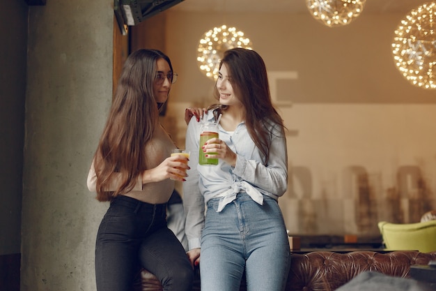 Mulheres elegantes em pé em um café e beber um cocktail