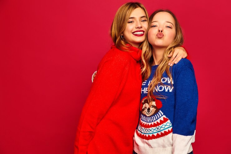 Foto grátis mulheres em suéteres quentes elegantes de inverno na parede vermelha