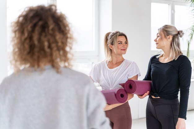 Mulheres em tiro médio segurando tapetes de ioga