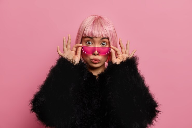 Foto grátis mulheres, estilo, moda, conceito de emoções. jovem impressionada com o cabelo rosa da moda, olhando por baixo dos óculos escuros, vestida com um suéter preto fofo, perde a fala de espanto, fica em pé