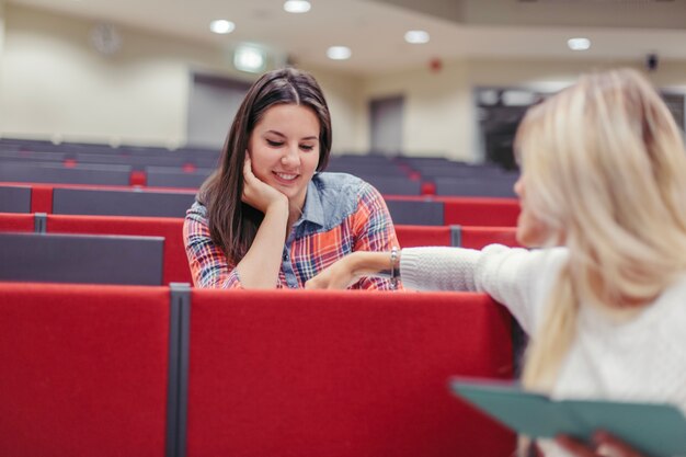 Mulheres falando enquanto estão sentadas na palestra